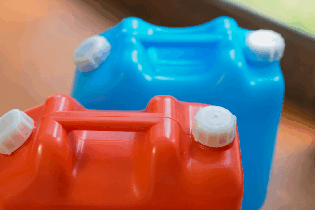 木の床の上に並べて置かれた赤と青のポリタンク。自然光が差し込み、白いキャップと持ち手の形状がはっきり見える。