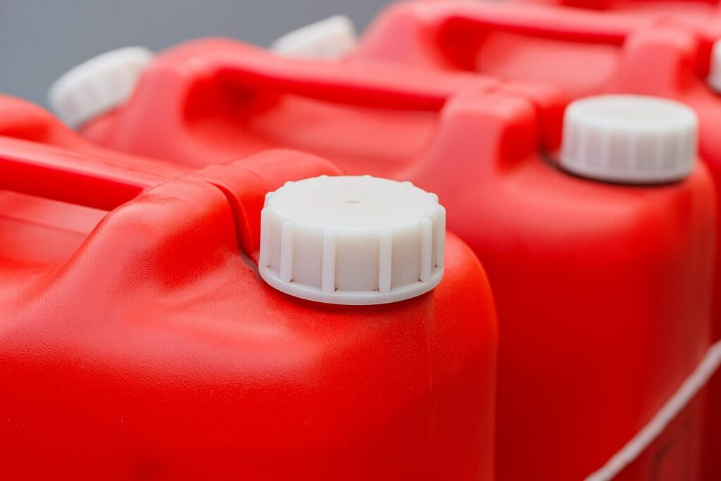 赤いポリタンクが並び、白いキャップ部分が手前に大きく映っている様子を写した画像