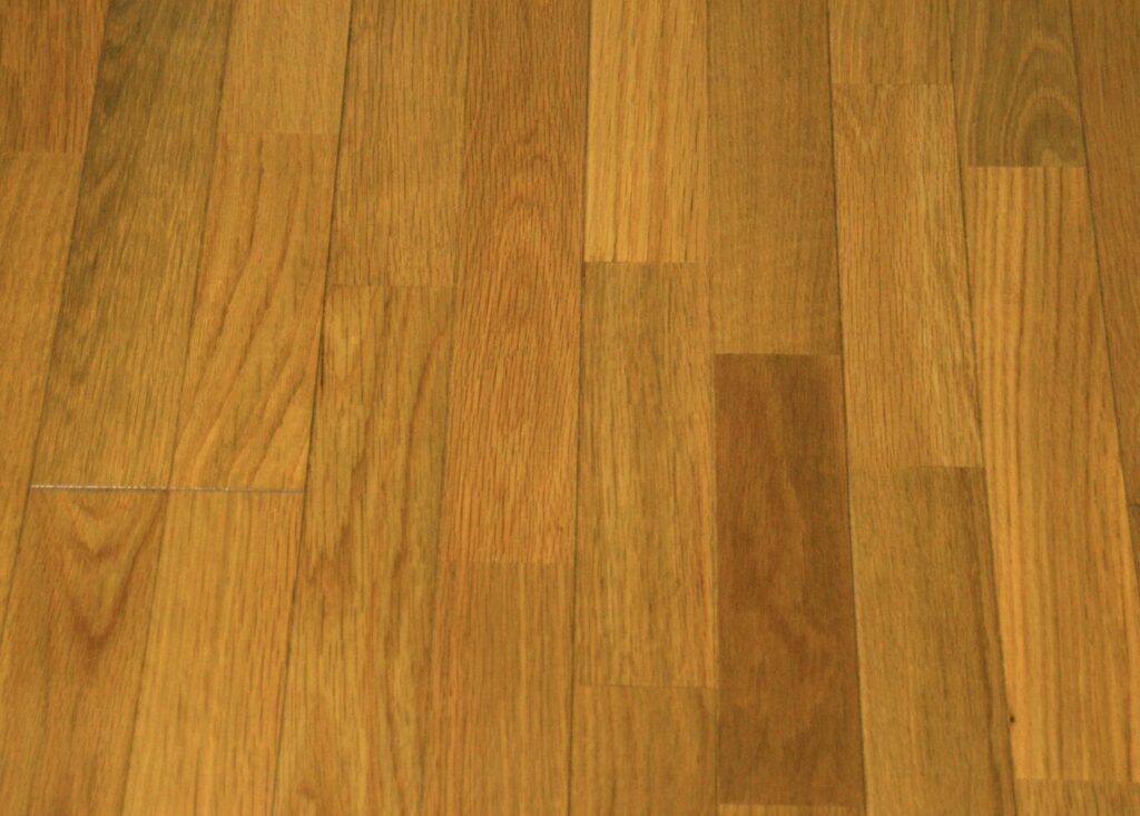 木目が美しいフローリング床のアップ。明るい茶色の板が並び、自然な色の濃淡が見られる。