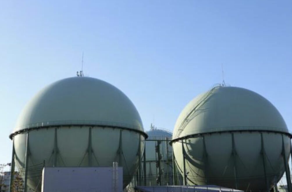都市ガスを貯蔵するためのガスホルダーが2基並ぶ様子。球形のタンクが青空の下にそびえ立ち、外周には補強フレームと点検用の階段が見える。