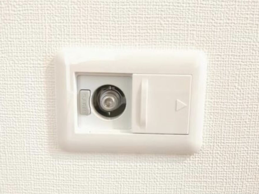 室内の壁面に設置されたガスコンセントの差し込み口が正面から見える状態で写っている。スライド式のカバーが横に配置され、使用時に開閉できる構造がわかる。