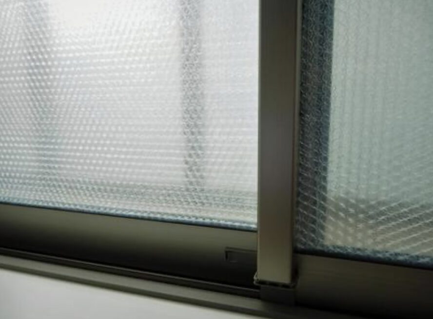 窓ガラスに気泡入りの断熱シートが全面に貼られ、室内側からその質感が見えている様子を写した写真