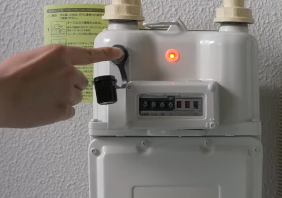 ガスメーター本体の復帰ボタンを指で押して安全装置を解除している様子
