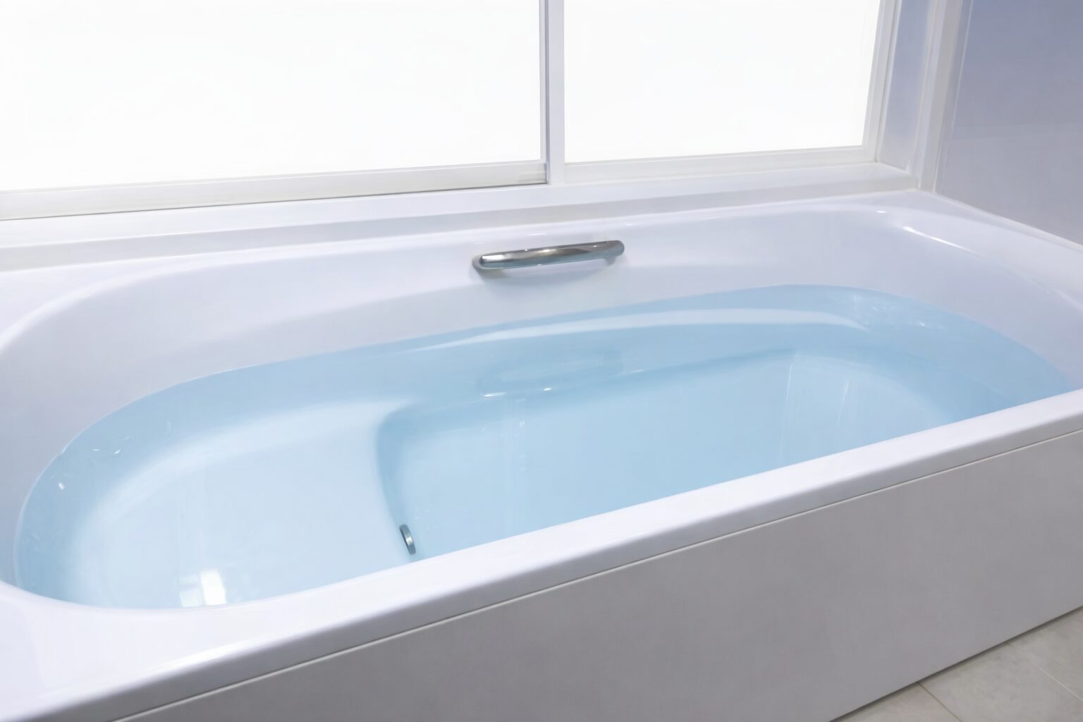 白い浴槽にお湯が張られ、明るい窓から自然光が差し込む清潔感のある浴室の様子