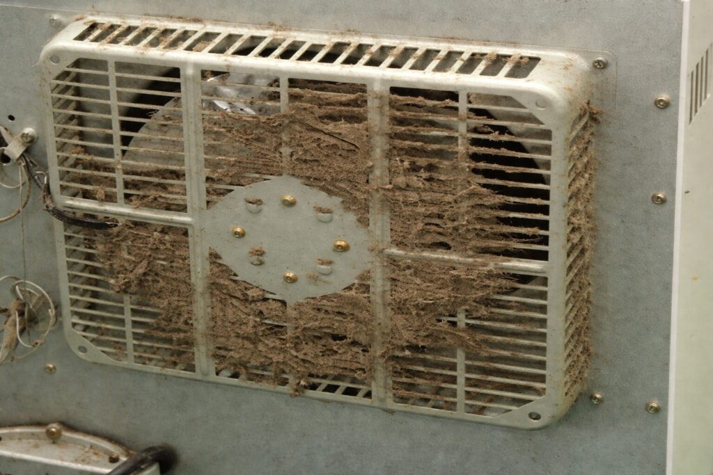 ホコリが大量に付着して目詰まりしている、暖房機器本体背面の冷却ファンカバーの状態がわかる様子