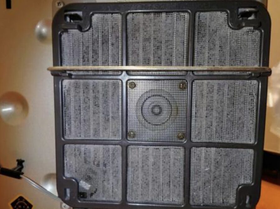 ストーブ内部の背面カバーを外した状態で、金属メッシュ状の燃焼部や内部パネルにホコリや汚れが付着している様子を写した写真