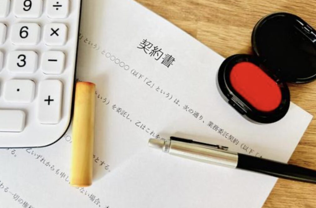 契約書のイメージ画像。机の上に電卓、印鑑、ペン、朱肉が並んでいる。