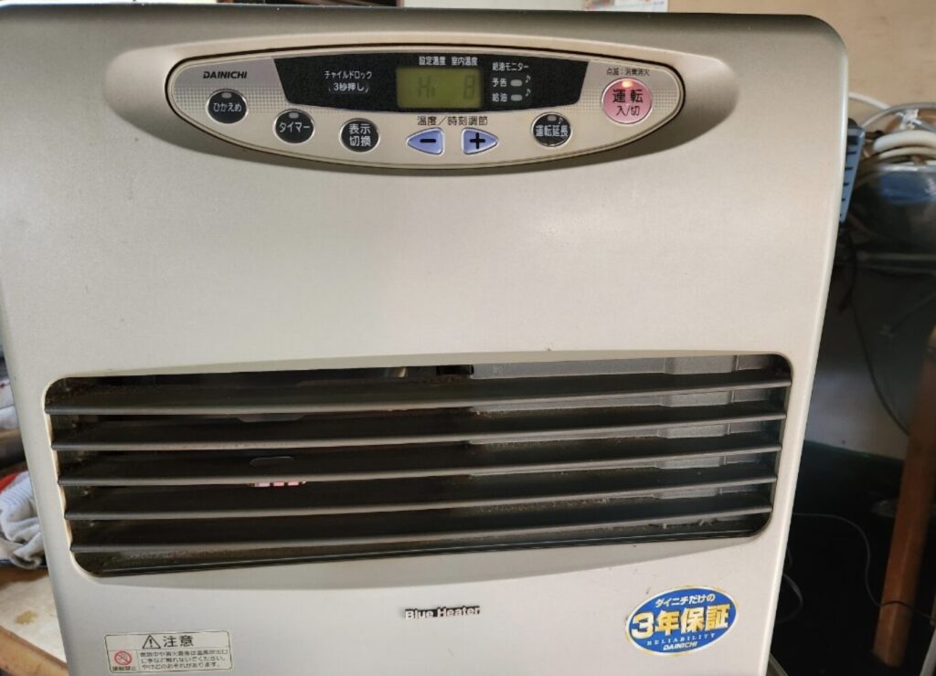 ダイニチ製の石油ファンヒーター本体正面を撮影した様子で、上部に操作パネルと表示画面、下部に温風の吹き出し口が配置されている。