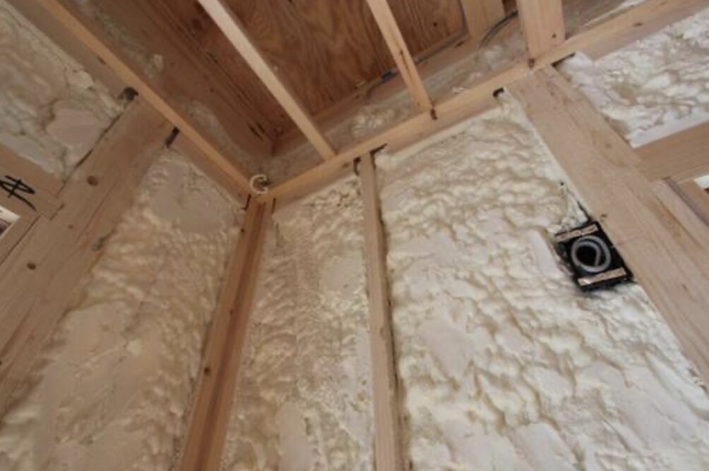 木造住宅の壁内部を写した写真で、柱と間柱の間に吹き付け発泡ウレタン断熱材が施工され、配線用のボックス周辺まで隙間なく充填されている状態が確認できる様子。