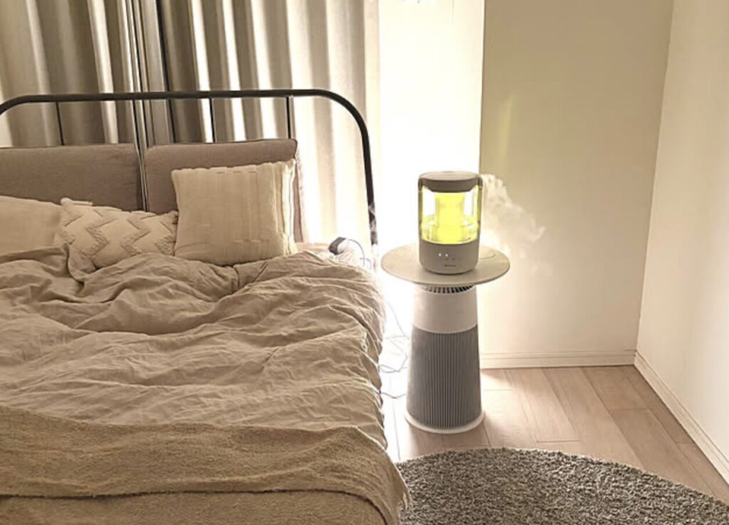 寝室のベッド横に設置されたスタンド型の加湿器からミストが広がり、落ち着いた照明の中で室内をうるおしている様子