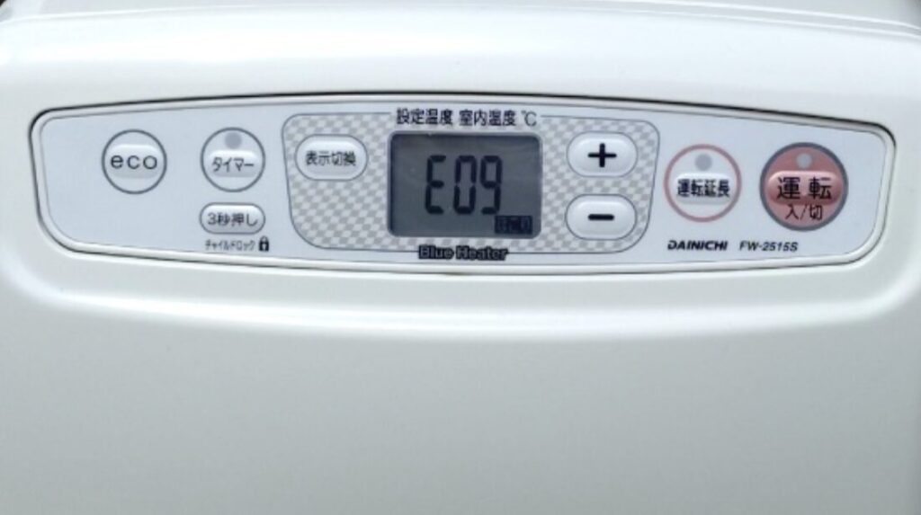 ダイニチ製石油ファンヒーターの操作パネルを正面から撮影した様子で、中央の液晶画面にエラーコード「E09」が表示されている状態。eco・タイマー・表示切換ボタンや、温度調整用のプラス・マイナスボタン、運転入切ボタンが並んでいる。