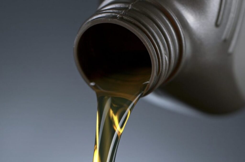 金属製の容器の注ぎ口から淡い黄色の灯油が流れ出ている様子を接写した画像で、液体の粘度や色味がはっきりと確認できる。