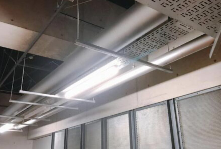 オフィスや事務所の天井に設置された直管蛍光灯照明。配線ダクトや天井設備と一体になって設置されている。