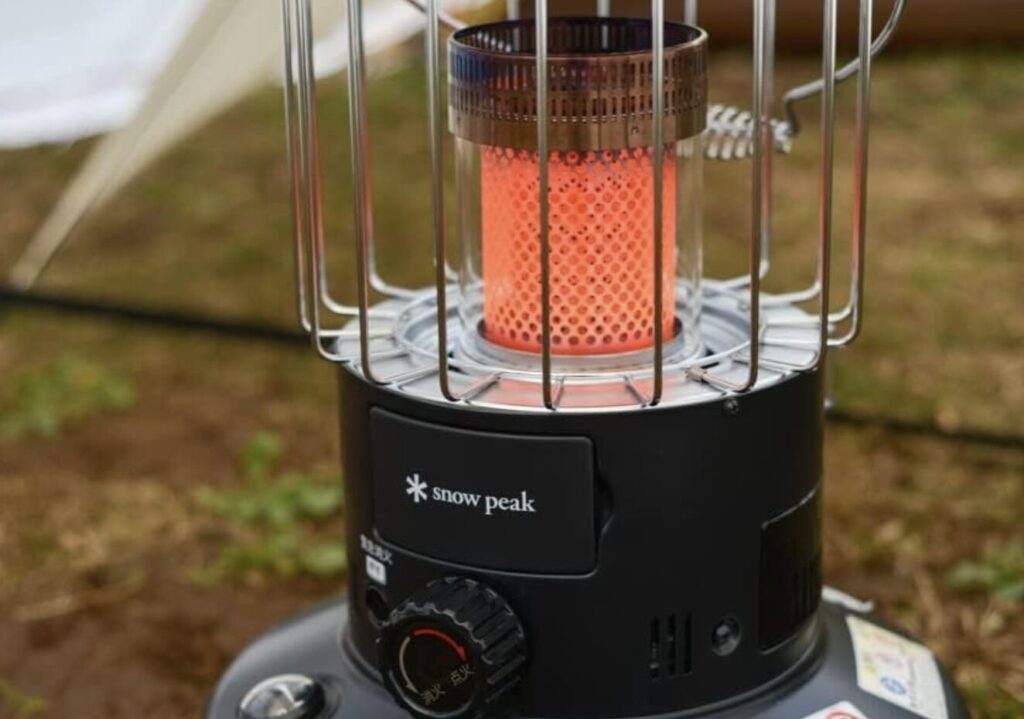 屋外で使用されている円筒形の暖房用燃焼器具で、赤く発熱した燃焼部が金属ガード越しに見える状態。