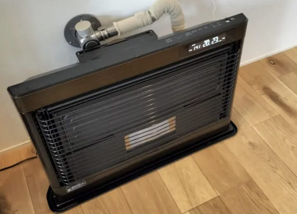 床置き型のFF式ストーブが室内に設置され、壁から給排気管が接続されている暖房設備の様子。