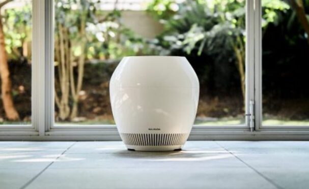 日差しの入る窓際の床に設置された、白色で丸みのあるデザインの気化式加湿器。