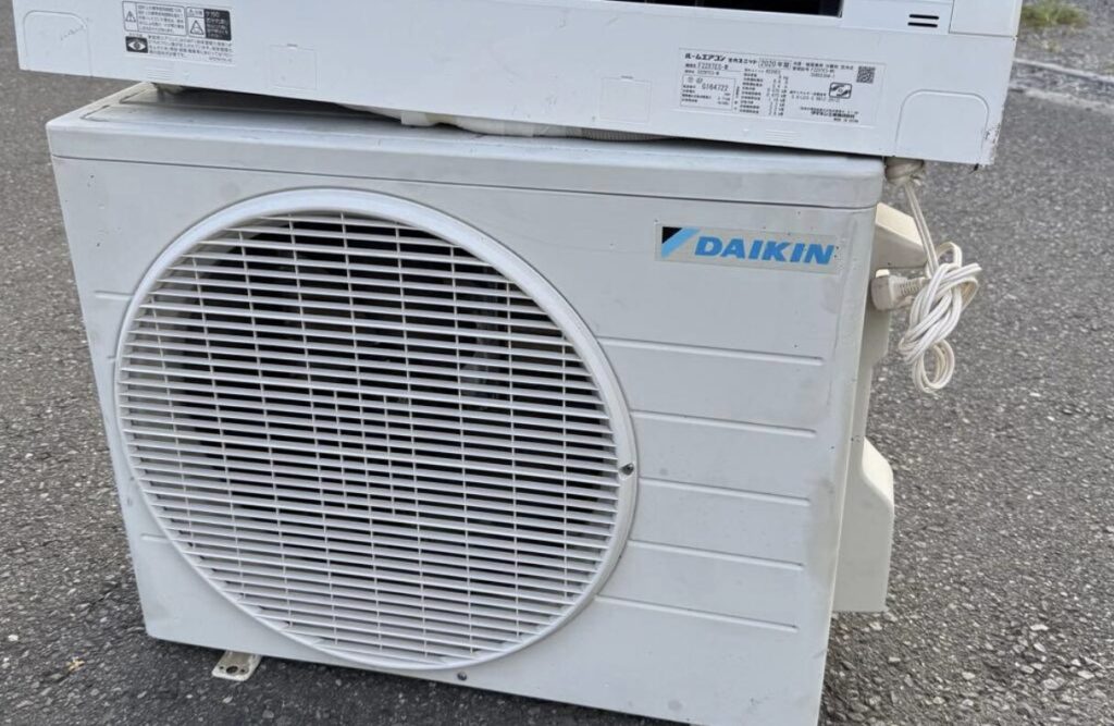 屋外に設置されたダイキン製エアコンの室外機。正面のファンガードと本体側面のロゴが確認できる。