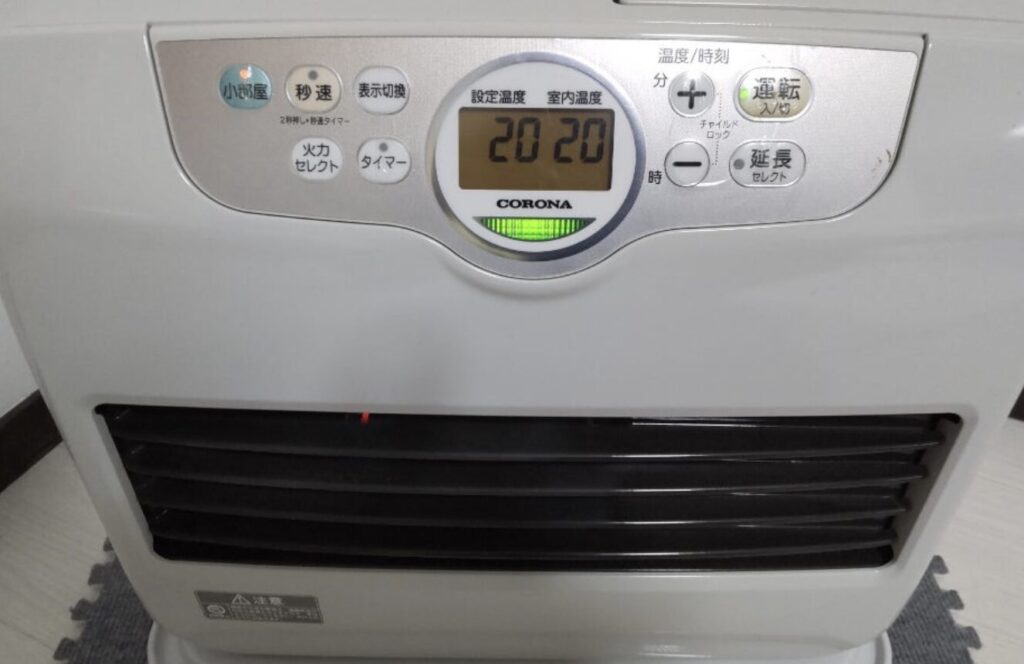 コロナ製石油ファンヒーターの操作パネルを正面から撮影した様子。設定温度と室内温度が「20」と表示され、運転ランプが点灯している。