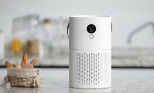 キッチンカウンター上に置かれた円筒形の空気清浄機。操作表示パネルが正面にあり、生活空間で使用されている。