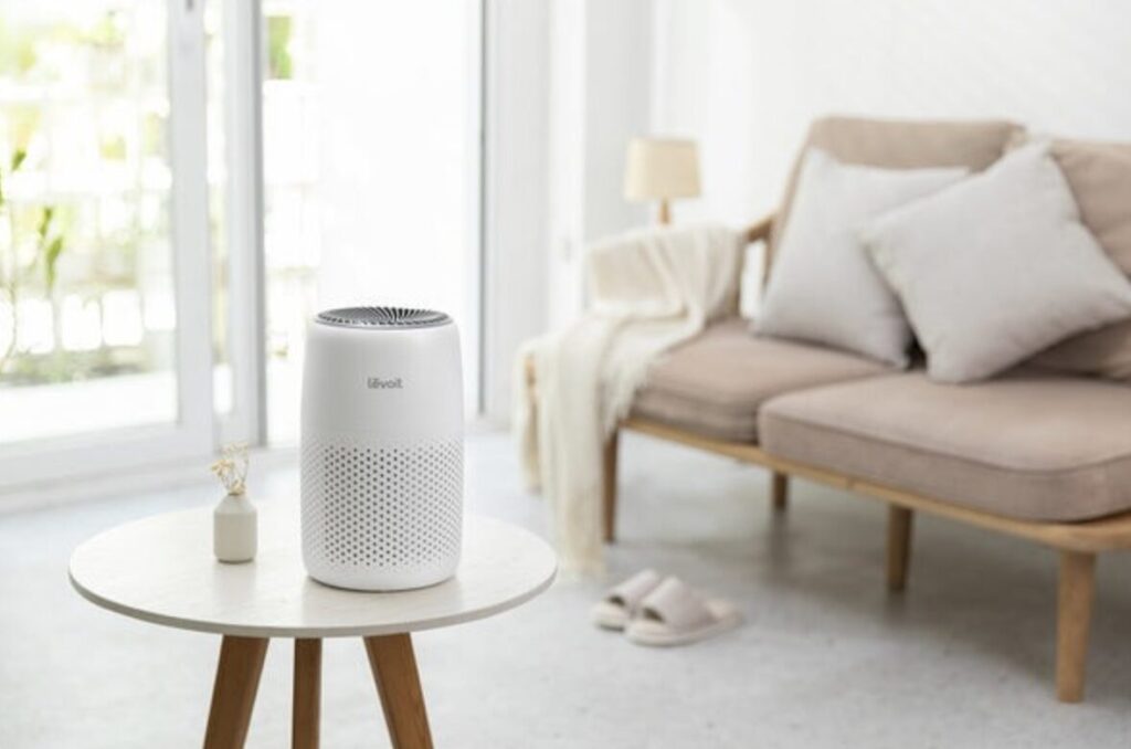 リビングのサイドテーブルに置かれた小型の白い空気清浄機。ソファや窓際のある明るい室内空間で使用されている。