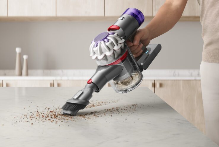 キッチンカウンター上の食べこぼしを、ハンディタイプのダイソン製コードレス掃除機で吸い取っている様子。