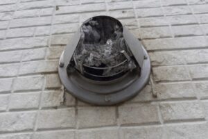 外壁の丸型排気口にホコリが詰まっている様子。乾太くんの排湿不良を示す詰まり事例。