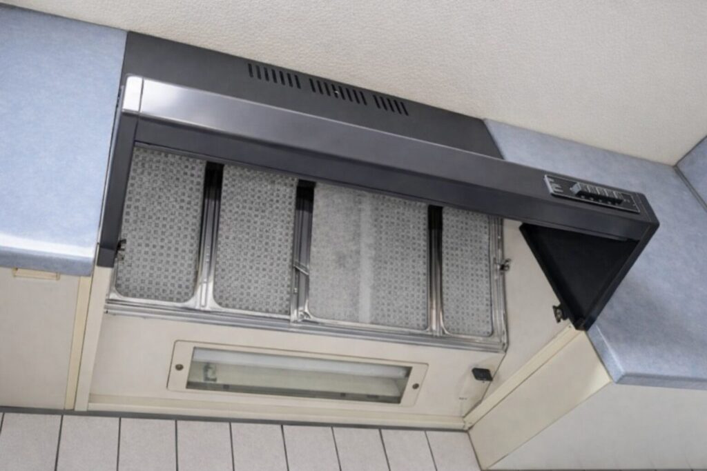 壁付けタイプのレンジフードの内部フィルター部分を下から撮影した写真。金属フィルターと照明カバーが見える状態。