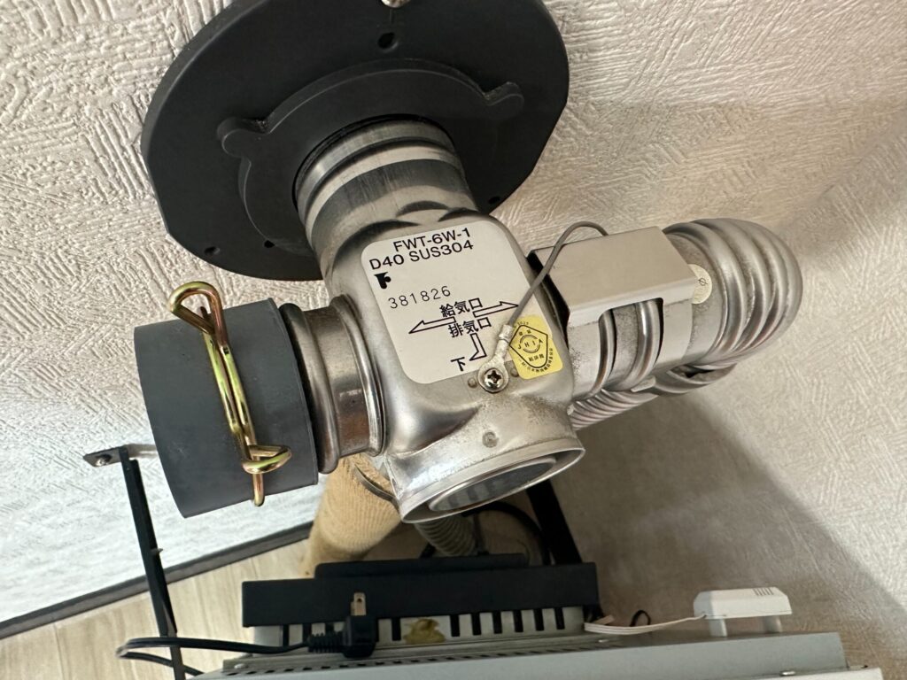 FF式ストーブの給排気トップ接続部の上部からの視点。給気口・排気口の向きと固定金具が確認できる状態