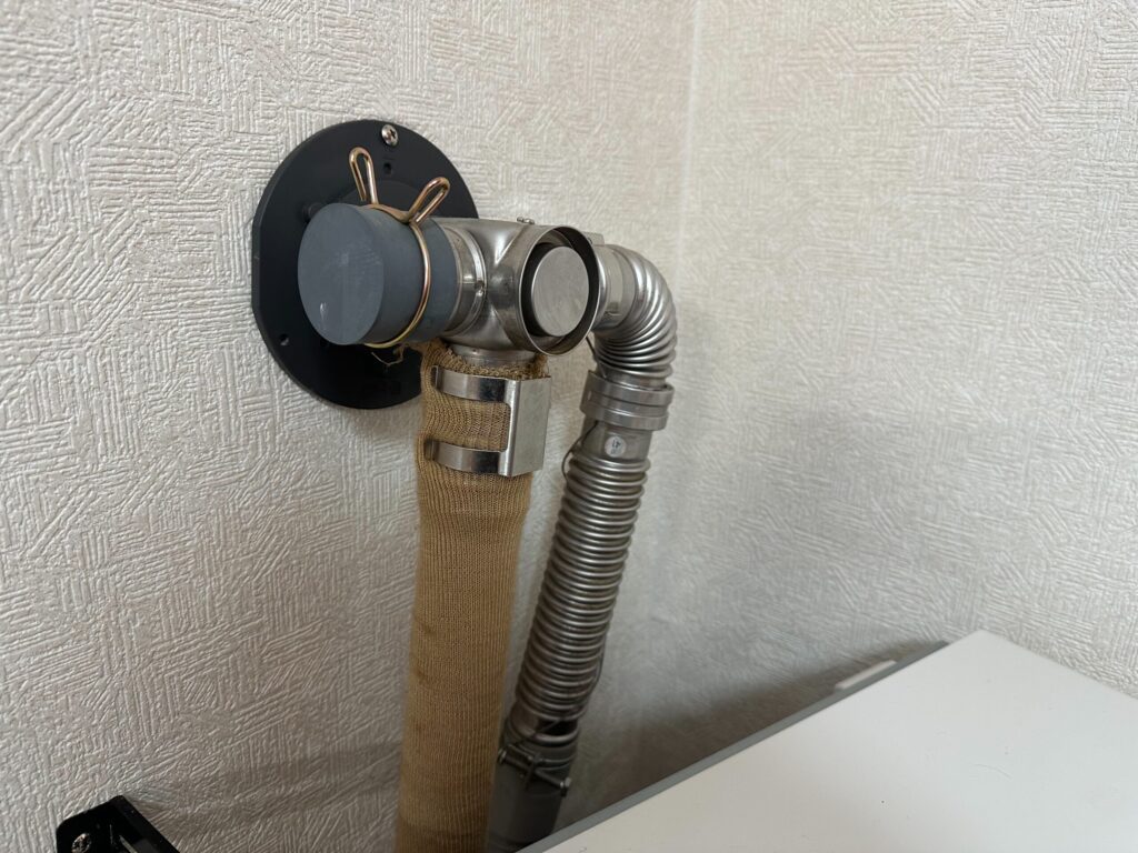 壁面に設置されたFF式ストーブの給排気トップ。外壁貫通部と排気エルボ接続部の様子