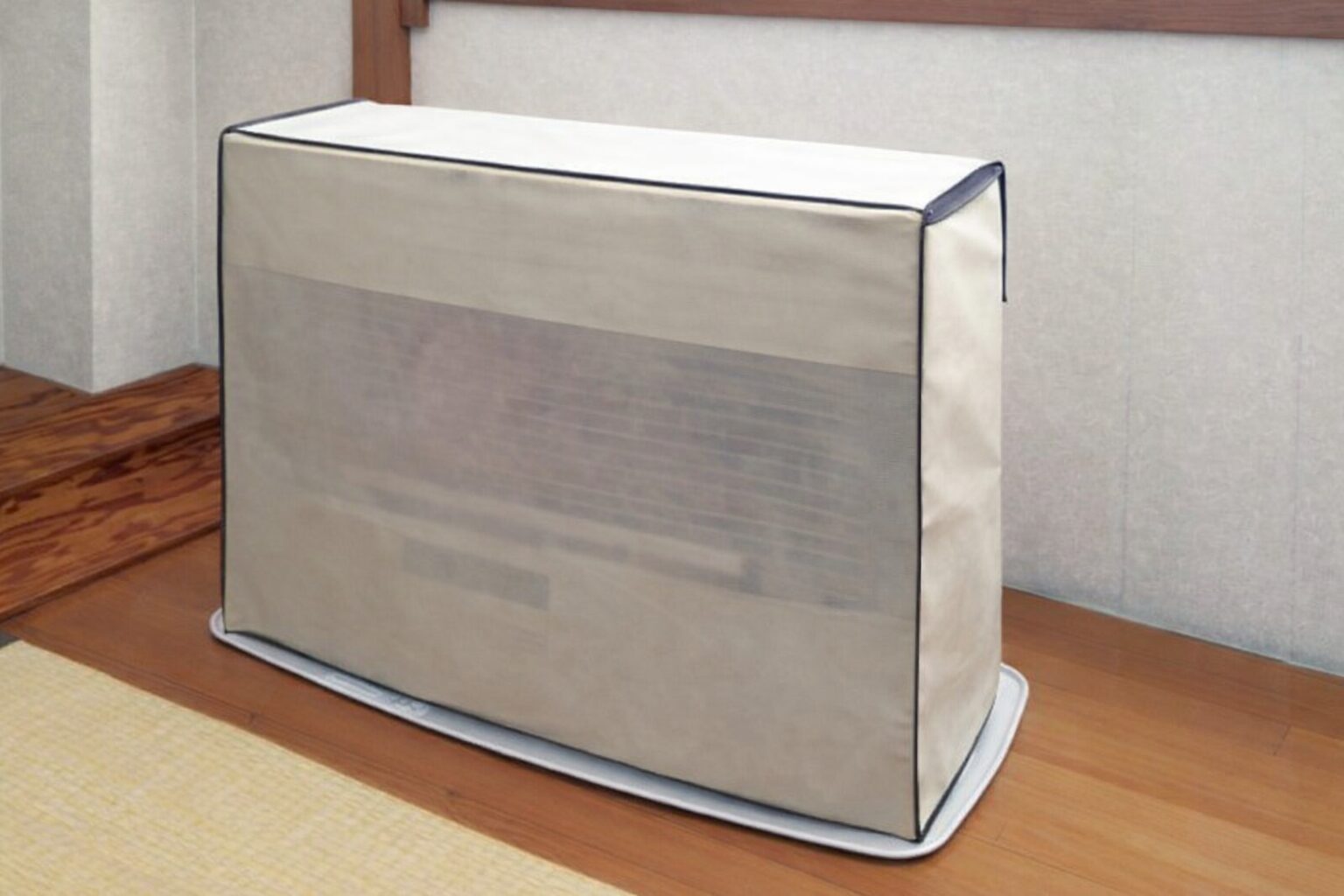 和室の畳とフローリングの境目に設置された石油ファンヒーターに、ベージュ色の専用カバーをかけて保管している様子。