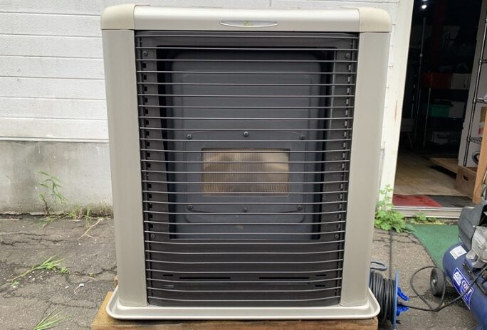 サンポット製のFF式石油暖房機本体。前面ガードと燃焼部の点検窓が確認でき、暖房機の外観が分かる。