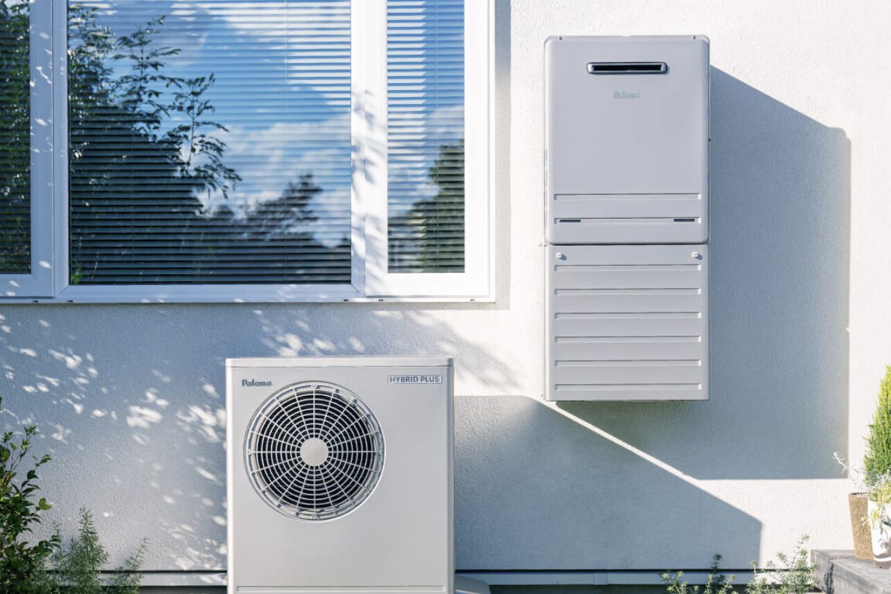 住宅外壁に設置されたパロマ製の給湯器とヒートポンプユニット。窓の下に室外機が配置され、給湯システム一式の設置状況が確認できる。
