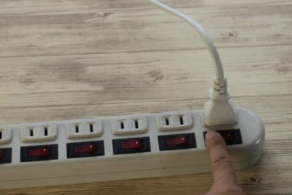 スイッチ付き電源タップのスイッチを指で操作している手元の様子