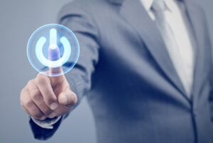 スーツ姿の人物が指で電源マークのアイコンを押しているイメージ写真
