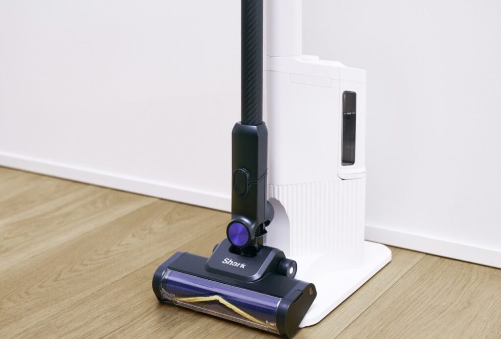 Shark製コードレス掃除機が専用スタンドに立てて収納され、フローリング床に設置されている様子