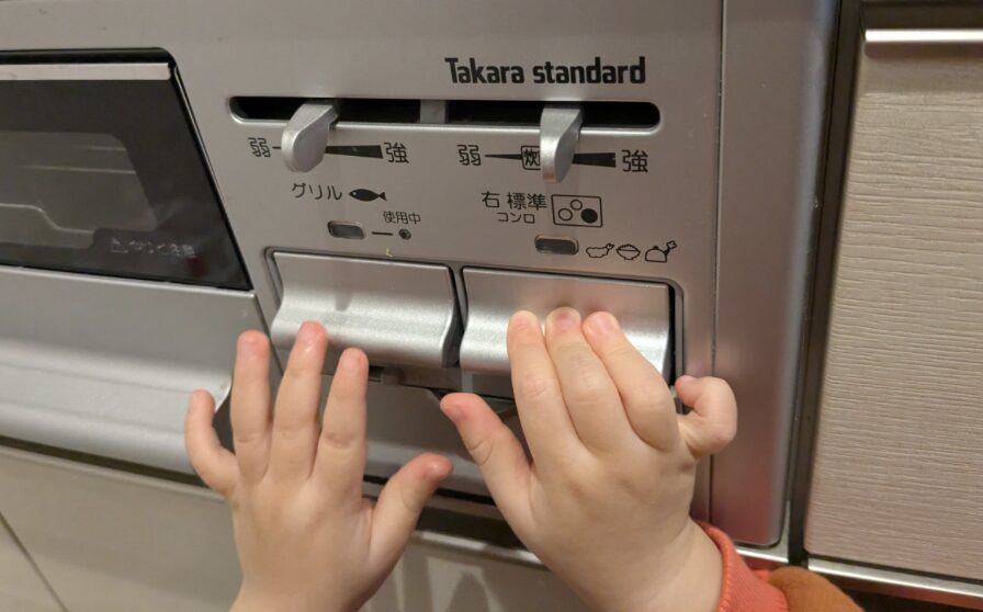 小さな子どもがビルトインガスコンロの操作ボタンに手を伸ばしている場面