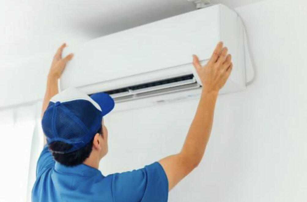 作業員が室内で壁掛けエアコン本体を取り付けている作業中の様子