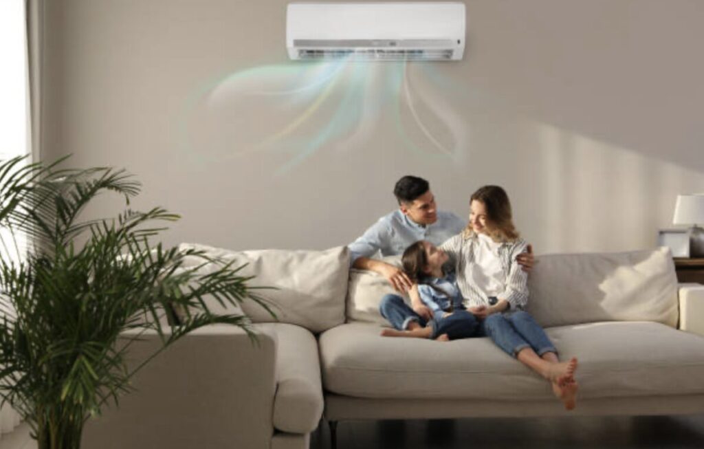 リビングの壁に設置されたエアコンから風が広がり、ソファに座る家族がくつろいでいる様子
