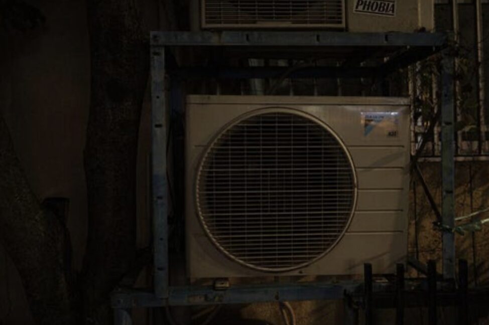 夜間に金属架台へ設置されたエアコン室外機の外観