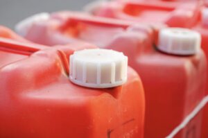 赤い灯油ポリタンクの白いキャップ部分をクローズアップした写真。複数のタンクが並んでいる保管風景。