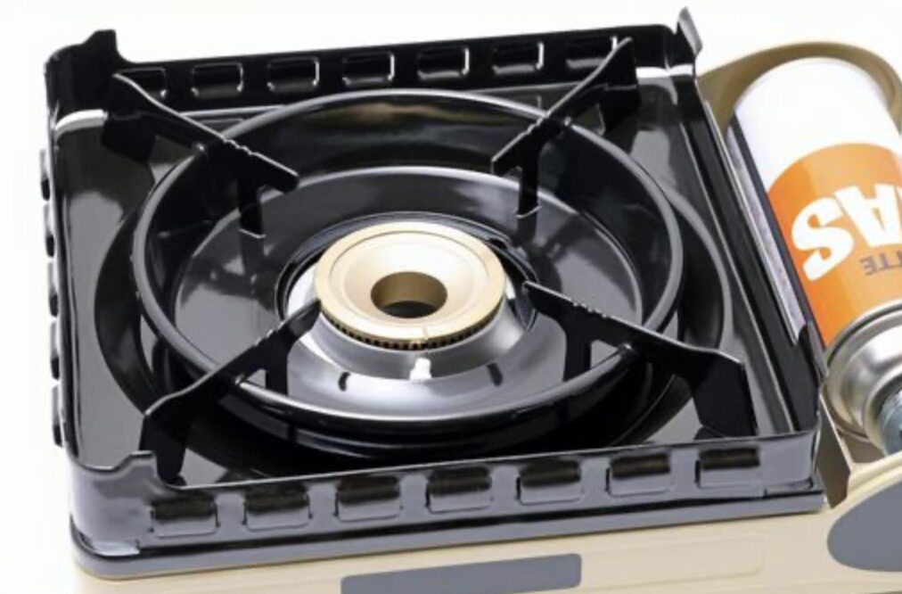 カセットコンロ全体の上面構造と、横に置かれたカセットガスボンベ。五徳とバーナーが見える状態。