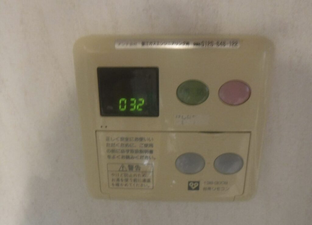 壁付け給湯器リモコンに「032」と表示されたデジタル画面。エラーコード表示のクローズアップ。