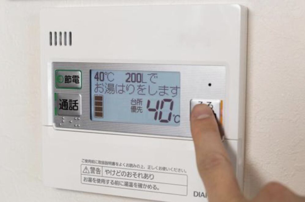 給湯器リモコンの操作パネルで40℃・200Lの湯はり設定表示。指で「ふろ」ボタンを押している様子。