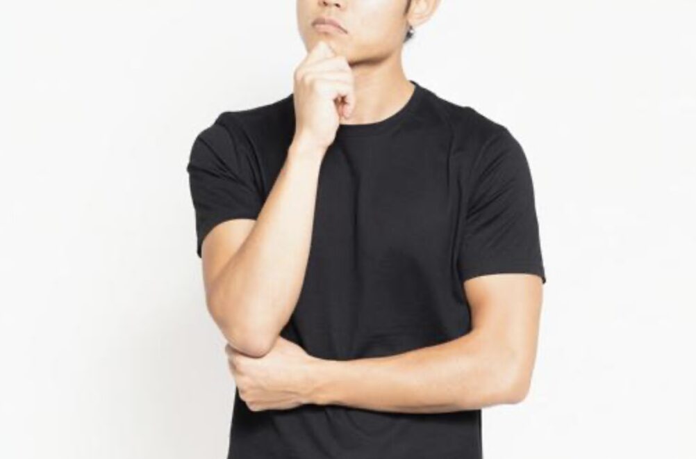 腕を組みながら顎に手を当て、考え込んでいる男性の上半身イメージ