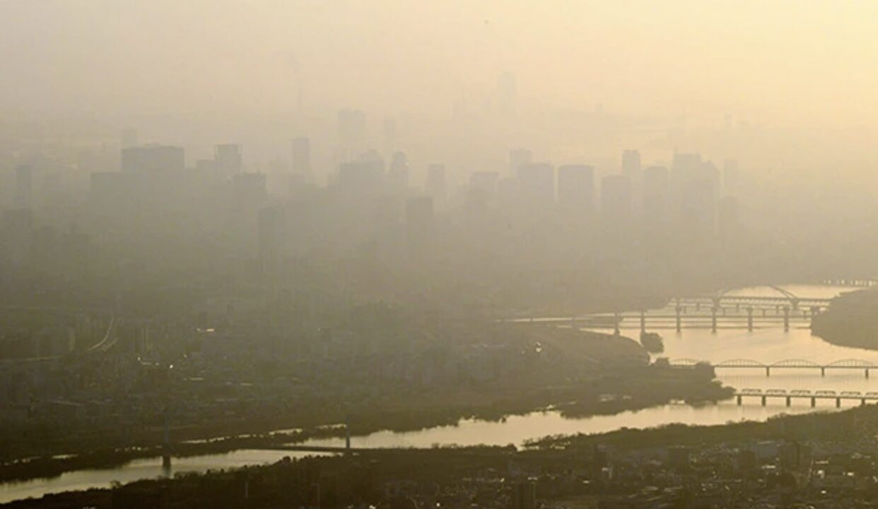 黄砂でかすむ河川と橋、遠景の高層ビル群が霞んで見える都市風景