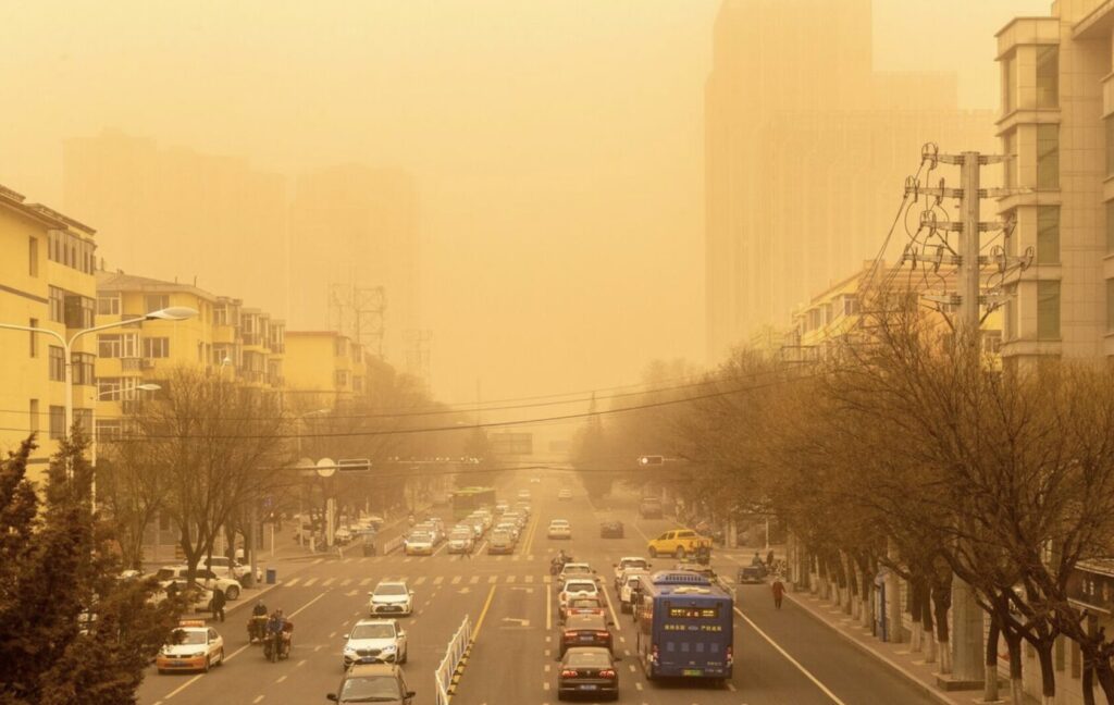 黄砂で視界が黄色くかすむ都市の幹線道路と走行する車両