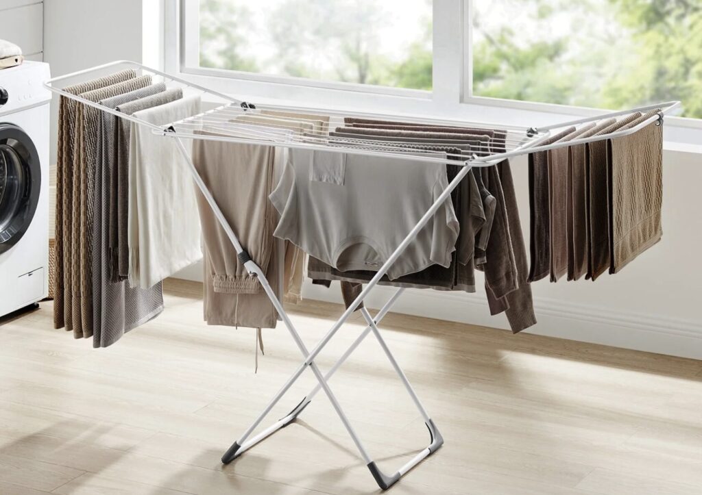 室内の物干しスタンドに洗濯物を干している様子と大きな窓から入る自然光