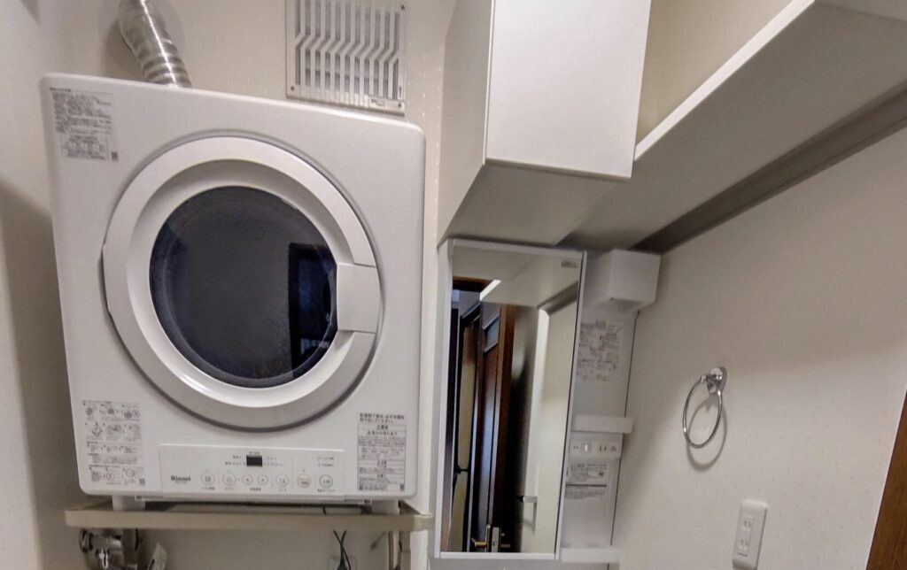 洗面所の棚上に設置されたリンナイ製ガス衣類乾燥機。換気ダクトが接続された設置例。