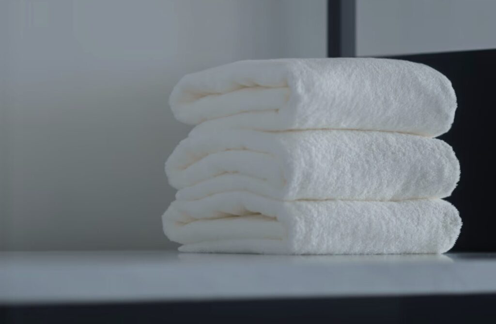 清潔感のある白いタオルが3枚重ねられている様子。ふんわりと仕上がった乾燥後のタオルイメージ。