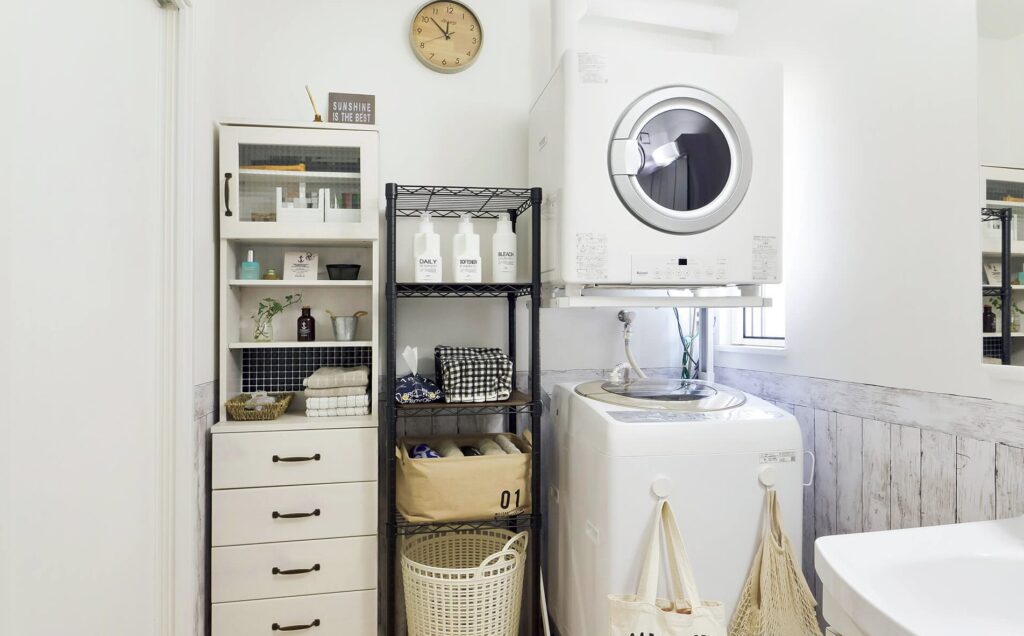 収納棚とアイアンラックが配置された洗面脱衣室。上部にガス衣類乾燥機、下に縦型洗濯機が設置された実例。